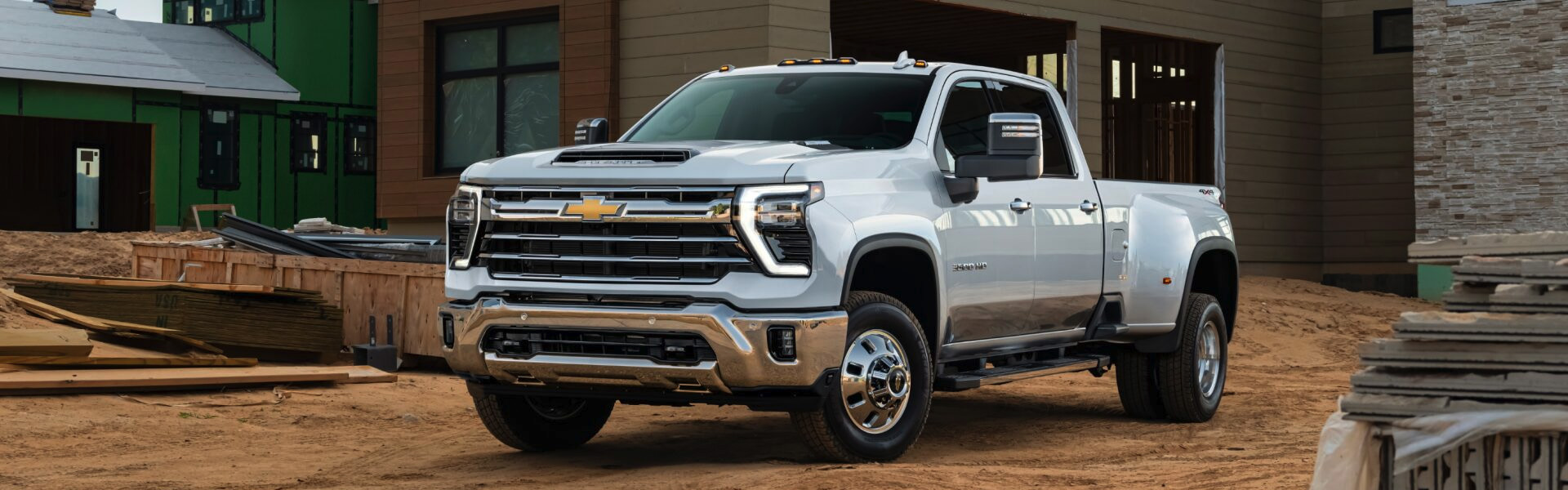 2025 Chevrolet Silverado 2500 HD white heavy-duty pickup truck parked at a construction site